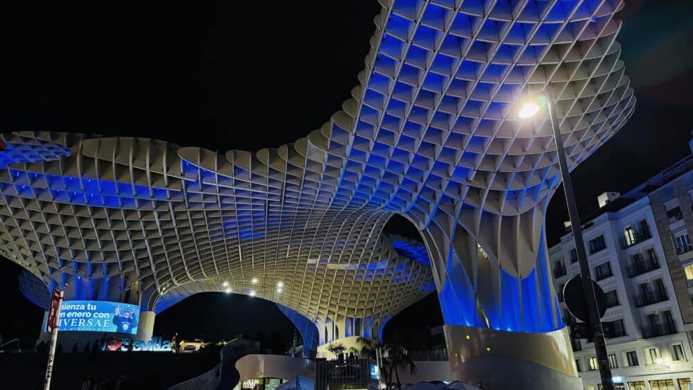 Vista de las Setas de Sevilla por la noche con luces de colores, arriba tiene un mirador a Sevilla